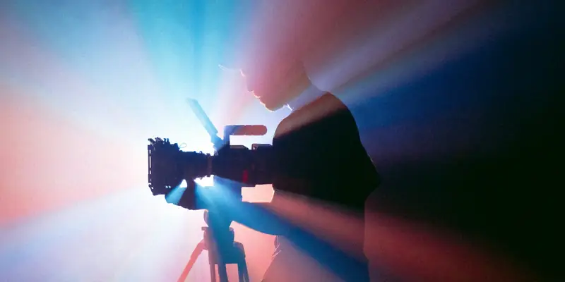 Videographer filming with a camera under studio lights