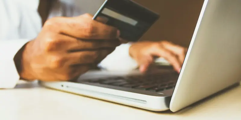Shopper paying online with a card on a laptop