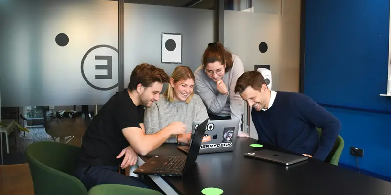 Agency team collaborating around laptops